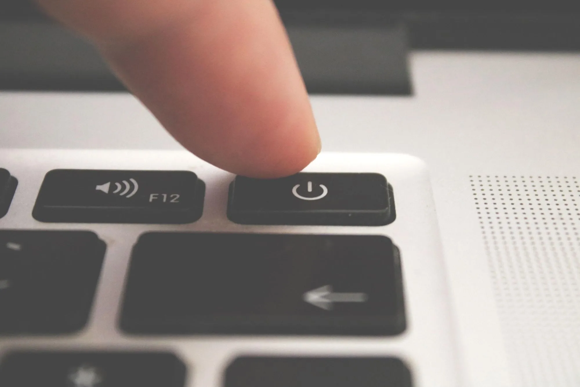 A zoomed in image of finger about to press the on/off button on a MacBook pro